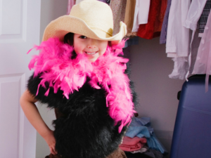 Child in cowboy hat and pink feather boa