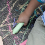 child's hand drawing with sidewalk chalk