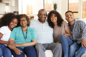 Grandparents with teen and young adult grandchildren sitting at home smiling to camera