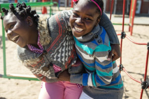 Two african-american girls playing in school playground at recess..