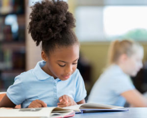 African American girl in charter school uniform reading a book